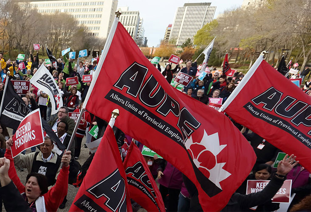 AUPE members carrying large red AUPE flags march together.