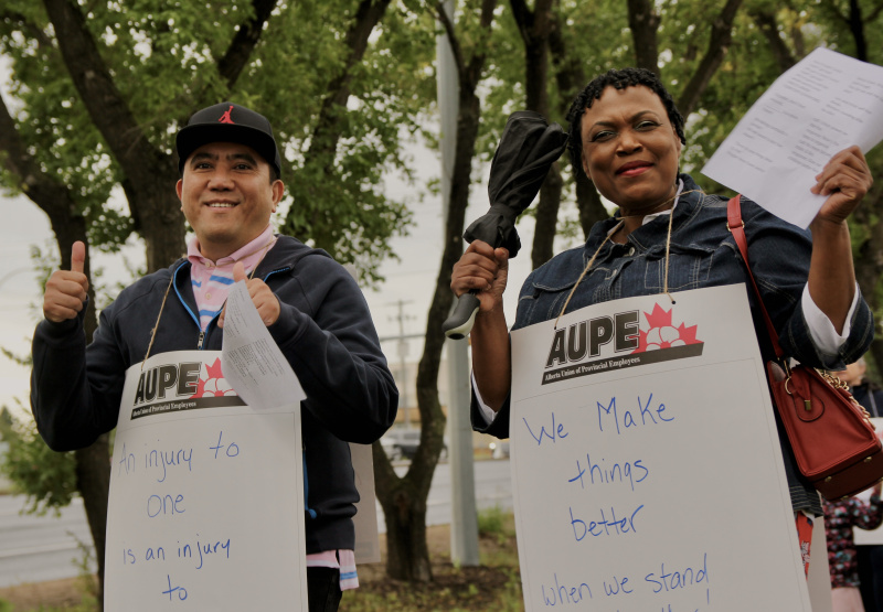 Two AUPE members show the thumbs up at a picket line at Misericordia Hospital.